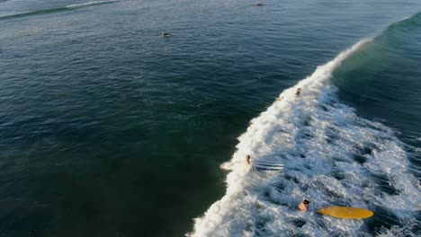 Aerial-view-moving-away-shot,-Surfers-gathering-on-the-beach-catching-some-waves-on-San-Juanico,-California-Sur,-Mexico