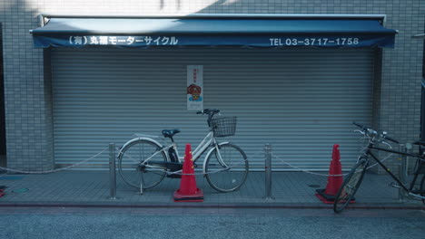 Bicicleta-Estacionada-Frente-A-Una-Tienda-Cerrada-Con-Gente-Pasando-Durante-El-Año-Nuevo-En-Medio-De-Una-Pandemia-En-Tokio,-Japón