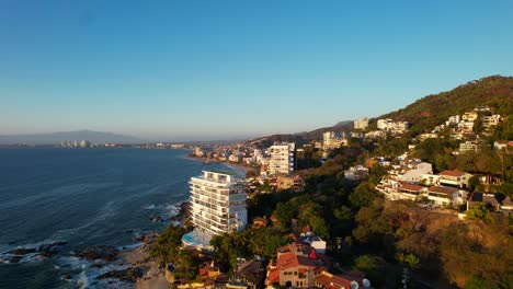 skyline-of-hotels-and-resorts-on-mountain-hills-in-Puerto-Vallarta-Mexico-at-sunset,-aerial