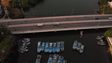 Large-bridge-where-multiple-vehicles-pass-over-a-river-with-moored-boats-of-Asian-architecture