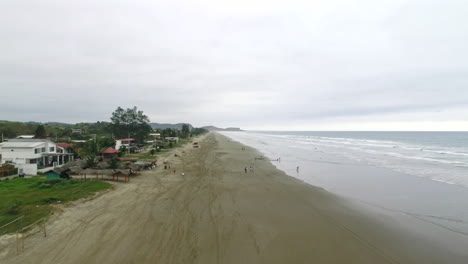 Vista-Aérea-De-Hoteles-Frente-Al-Mar-Y-Gente-Caminando-En-La-Playa-En-Un-Día-Nublado-En-Santa-Elena,-Ecuador