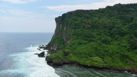 Hohe-Bergklippen-Von-Uluwatu-In-Bali-Mit-Meereswellen,-Die-Auf-Felsen-Krachen,-Antenne