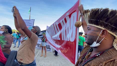 Indigene-Brasilianer-Mit-Gefiederten-Kopfbedeckungen-Halten-Ein-Banner-Zum-Protest-Vor-Dem-Obersten-Gerichtshof-Von-Brasilien-Gegen-Mord-Und-Gewalt-Gegen-Dom-Phillips-Und-Bruno-Pereira