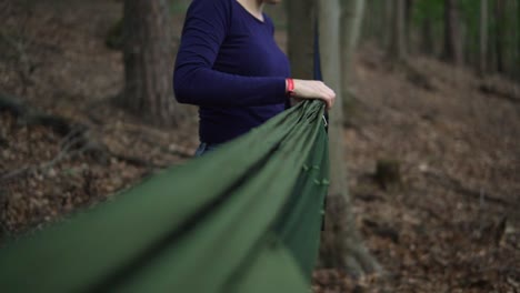 Slow-motion-shot-of-a-women-attaching-a-hammok-to-a-carabiner-so-she-can-fix-the-hammok-between-two-trees-in-the-forest-in-germany