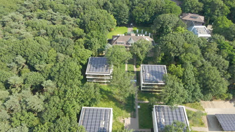 Aerial-of-small-office-buildings-with-solar-panels-on-rooftop-in-a-green-forest