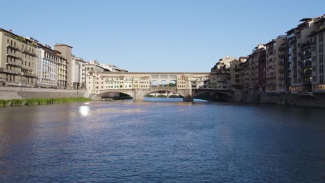 Aerial-over-the-river-to-Ponte-Vecchio-old-bridge,-medieval-historic-building-in-Florence,-Italy