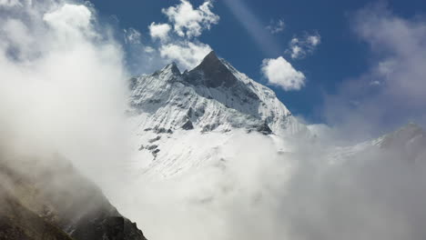 Epic-drone-shot-going-into-clouds-of-a-snowy-mountain-in-the-Annapurna-mountains,-Nepal