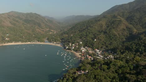 Bungalows-And-Boats-At-The-Beachfront-Of-Yelapa-Town-Resort-With-Towering-Forest-Mountains-In-Jalisco,-Mexico