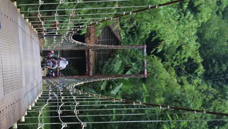 suspension-bridge-over-the-river-with-motorcycle-crossing-on-it-in-the-morning-in-Sukabumi,-west-java,-Indonesia-on-May-4,-2022