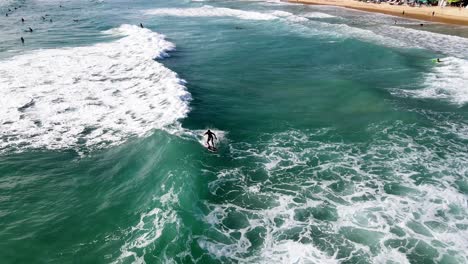 Luftflug-über-Surfer,-Die-Wellen-Auf-Türkisfarbenem-Wasser-Vor-Kata-Beach-In-Phuket-Fangen