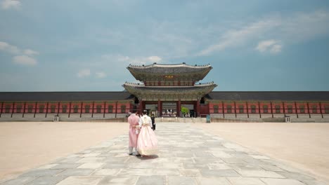 Palacio-Gyeongbokgung---Pareja-Coreana-Usando-Hanboks-Revisa-Fotos-En-El-Teléfono-De-Pie-Junto-A-La-Puerta-Heungnyemun