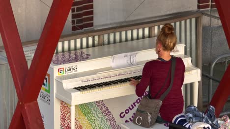 Local-woman-plays-public-piano-decorated-with-rainbows-and-LGBTQ+-pride-theme-for-Pride-Month-in-June