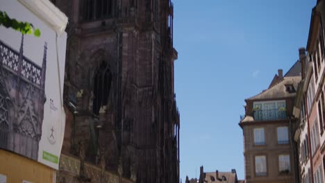 Bike-rack-and-tourists-walking-near-scenic-large-gothic-Cathedral,-the-Grand-Rue-De-Colmar-and-surrounding-architecture-in-downtown-Strasbourg,-France