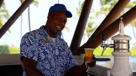Smiling-bartender-at-an-all-inclusive-resort-holding-a-beer-in-a-cup