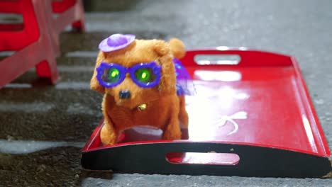 Ein-Stationäres-Filmmaterial-Eines-Gehenden-Und-Bellenden-Spielzeughundes-Mit-Leuchtenden-Augen,-Der-Eine-Sonnenbrille-Und-Einen-Kleinen-Hut-Trägt