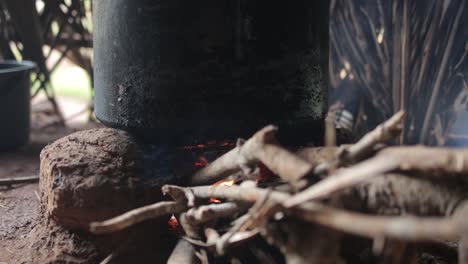 Close-up-low-POV-shot-of-pot-over-campfire-in-hut,-cooking-in-Indian-style