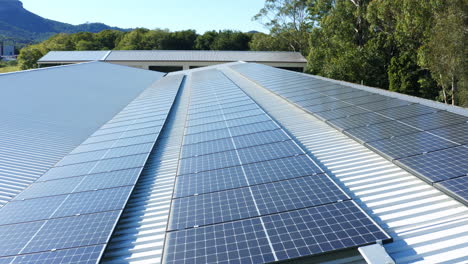 Luftdrohnenansicht-über-Sonnenkollektoren-Aus-Erneuerbaren-Energiequellen-Auf-Dem-Dach-Mit-Blick-Auf-Die-Berge,-4k