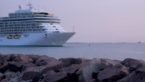 Großes-Weißes-Kreuzfahrtschiff-Seven-Seas-Splendor,-Das-Im-Hafen-Von-Liepaja-Ankommt,-Goldene-Stunde-Am-Frühen-Morgen,-Wassertransport,-Ostsee,-Urlaub,-Steinpier-Im-Vordergrund,-Mittlere-Aufnahme