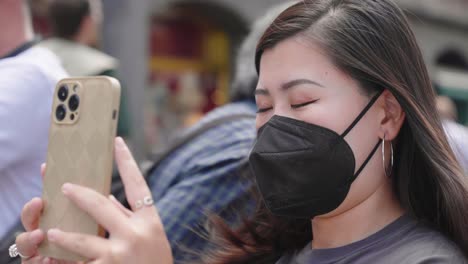 Hermosa-Joven-Asiática-Con-Mascarilla-Tomando-Fotos-Con-Un-Teléfono-Inteligente-En-El-Centro-De-La-Ciudad-De-Bruselas,-Bélgica