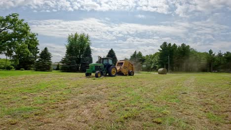 John-Deere-tractor-pulling-a-Vermeer-hay-baler-thru-a-cut-alfalfa-field-to-make-round-hay-bales