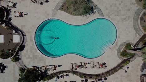 Top-view-of-an-empty-swimming-pool,-person-is-jumping-in-it-and-swims-across