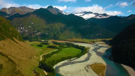 Breathtaking-aerial-landscape-of-Mountain-Valley-Track-by-the-river-in-Mount-Aspiring-National-Park,-New-Zealand-on-a-summer-day