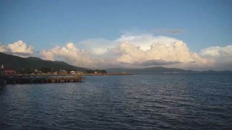Time-lapse-of-Fluffy-Clouds-by-the-Pier-with-Green-Mountains-in-Background