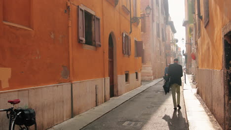 Slow-motion-clip-of-a-narrow-street-in-Verona,-Italy,-with-a-business-man-walking-down-it