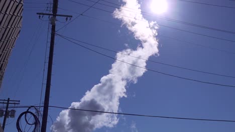 Steam-venting-into-sky-from-factory-wide-angle-looking-up