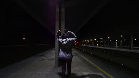 Total-shot-of-a-girl-putting-a-hoody-on-a-train-station-at-night