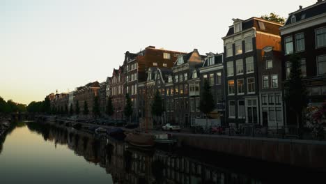 An-Amsterdam,-Netherlands-neighborhood-in-the-early-morning-light-with-the-houses-reflecting-in-the-water-of-the-canal