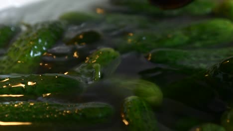 Cucumbers-float-in-a-bowl-full-of-water,-they-are-stirred-with-a-spoon