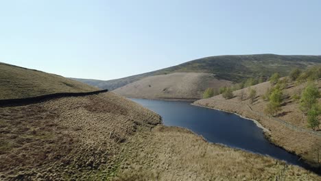 Aerial-shot-ascending-from-close-to-the-water-revealing-a-stream-which-feeds-the-mouth-of-Kinder-Reservoir,-Peak-District,-UK