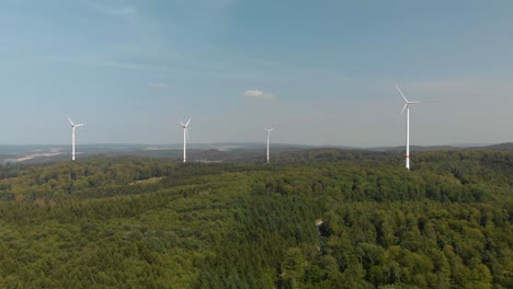Aerial-dolly-shot-of-a-cluster-of-wind-turbines-in-the-German-countryside,-bright-blue-sky-day