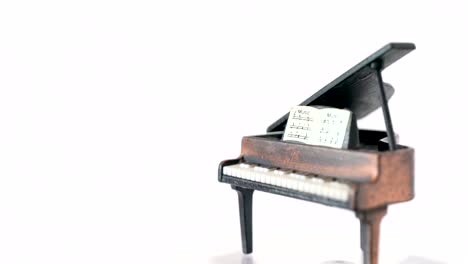 Metal-grand-piano-music-toy-rotating-around-in-studio-white-background
