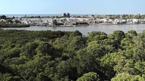 Drone-4K-flyover-of-lush-green-park-toward-inland-waterway-and-ocean