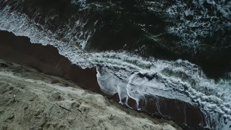 Drone-shot-over-crashing-ocean-waves-and-rocky-cliff