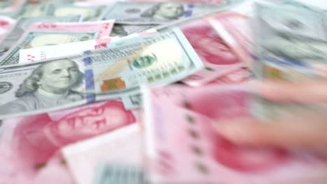 Chinese-and-American-paper-money,-close-up-a-hand-push-away-cash-money-on-the-table,-concept-idea-of-interference-and-loss