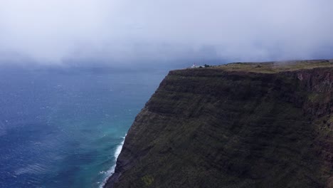 Madeira,-Portugal---Großer-Blauer-Ozean,-Der-Die-Schroffe-Klippe-Mit-Leuchtturm-An-Der-Spitze-Umgibt---Luftdrohnenaufnahme