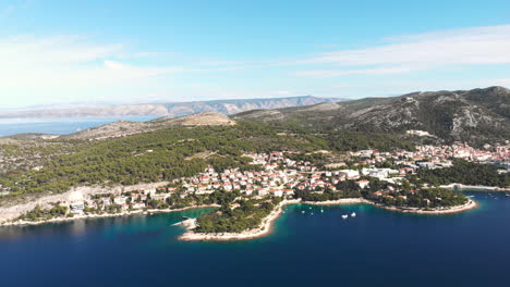 Drone-pushing-down-to-the-very-beautiful-island-of-Hvar,-revealing-many-mediterran-buildings-and-boats-of-the-city-Hvar