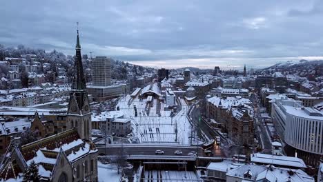 Aerial-push-in-drone-video-of-the-central-station-and-the-old-town-covered-with-snow,-Sankt-Gallen,-St