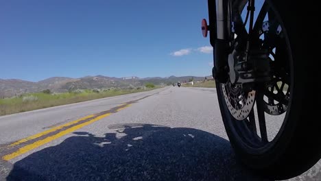 Bikers-trip-riding-highway-on-motorcycle,-front-wheel-low-angle-view
