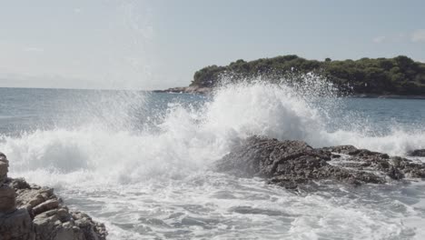 Slow-motion-shot-of-crashing-waves-on-rocks-at-shore-during-sunny-day-in-Pula,Croatia