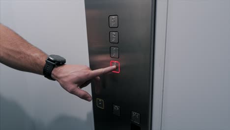 Close-up-shot-male-hand-press-metal-button-to-call-the-elevator-after-which-it-glows-red-floor-slow-motion
