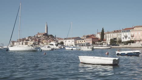Static-wide-shot-of-anchored-sailing-boats-and-yachts-on-bay-and-island-and-church-of-Rovinj-in-background