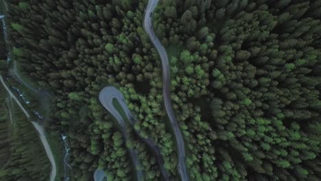 Drone-view-of-mountain-road-with-pine-trees-at-twilight-in-Dolomites,-Italy