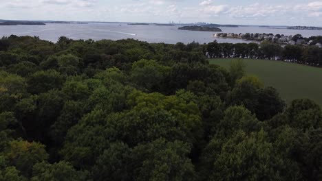 Gliding-low-over-trees-to-reveal-Boston-harbor-and-city-skyline