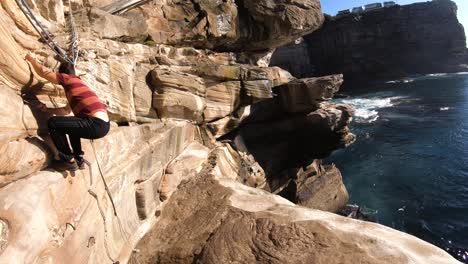 A-man-climbs-a-bouldering-route-on-a-dramatic-Sydney-coastal-cliff-face
