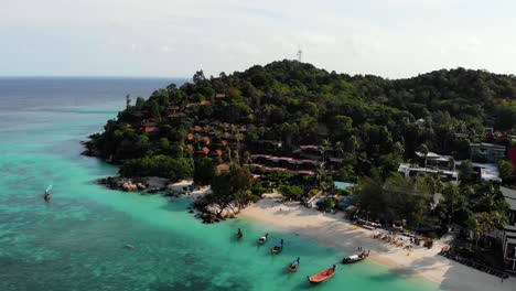 Aerial-view-of-stunning-tropical-coastline-with-dark-rocks-and-luxury-houses-by-sand-beach-in-Thailand
