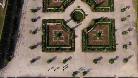 Aerial-view-of-french-garden-of-Alden-Biesen-Castle-in-Belgium,-Germany-with-group-of-people-walking-and-talking-on-a-bright-sunny-day